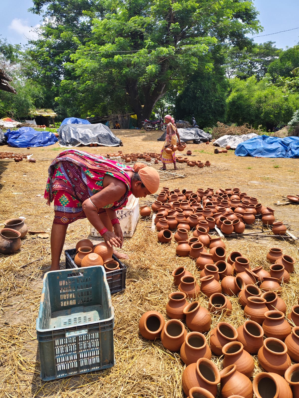 Women arranging rows of finished terracotta pots outdoors in Kumbharguda